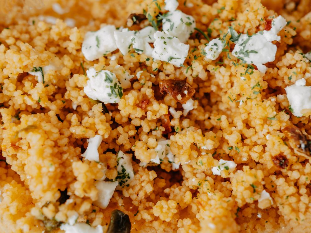 Close-up of couscous with herbs and crumbled cheese.