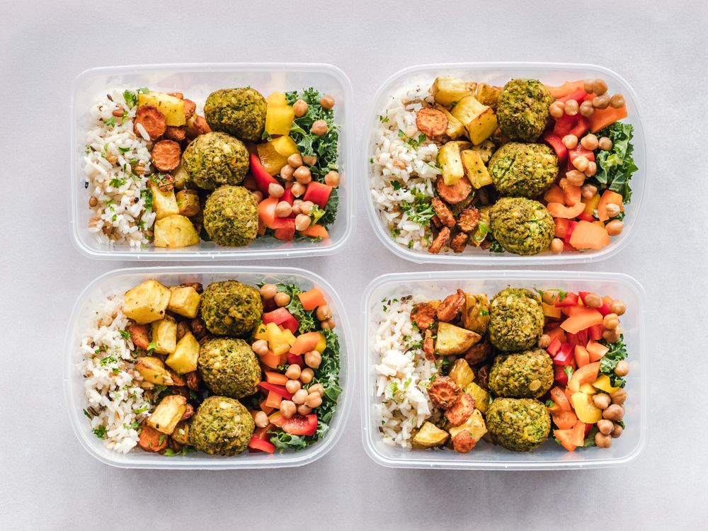 Several prepared containers with grains, chickpeas, falafel and vegetables.
