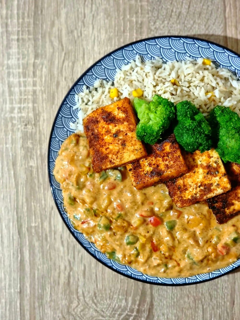 Tofu, rice and broccoli arranged on a patterned plate.
